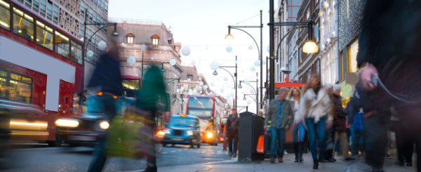 Busy sidewalk and roadway with a blur of cars, buses, and pedestrians