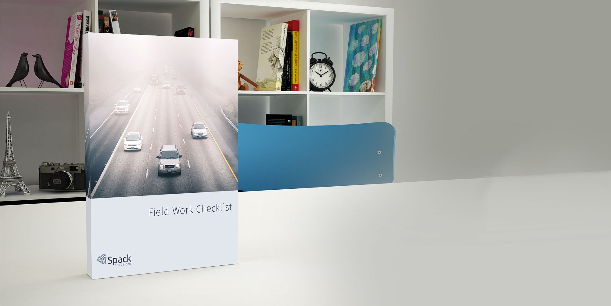 The Field Work Checklist Book standing vertically on a table with a white bookshelf in the background
