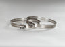 Two silver worm drive hose clamps laying horizontally on a table